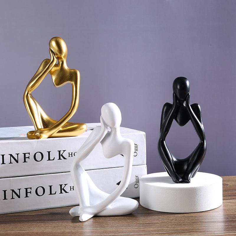 Trio de mini esculturas abstratas estilo pensador em dourado, branco e preto sobre livros e pedestal — Mova Decor