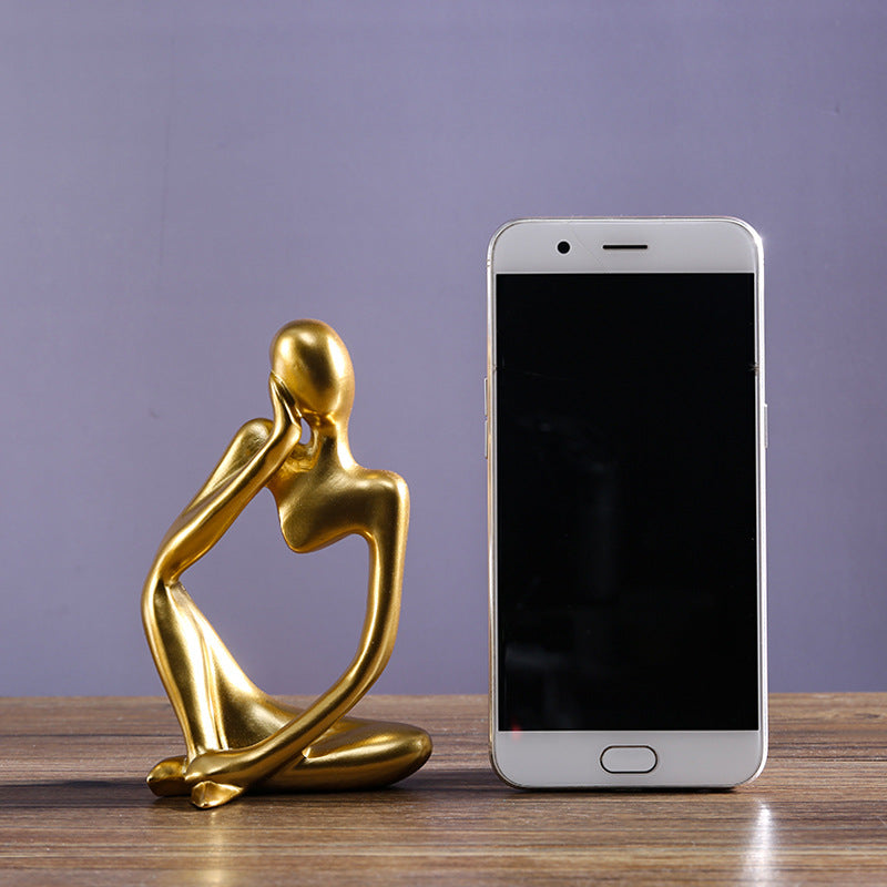 Mini escultura dourada estilo pensador ao lado de smartphone para referência de escala — Mova Decor